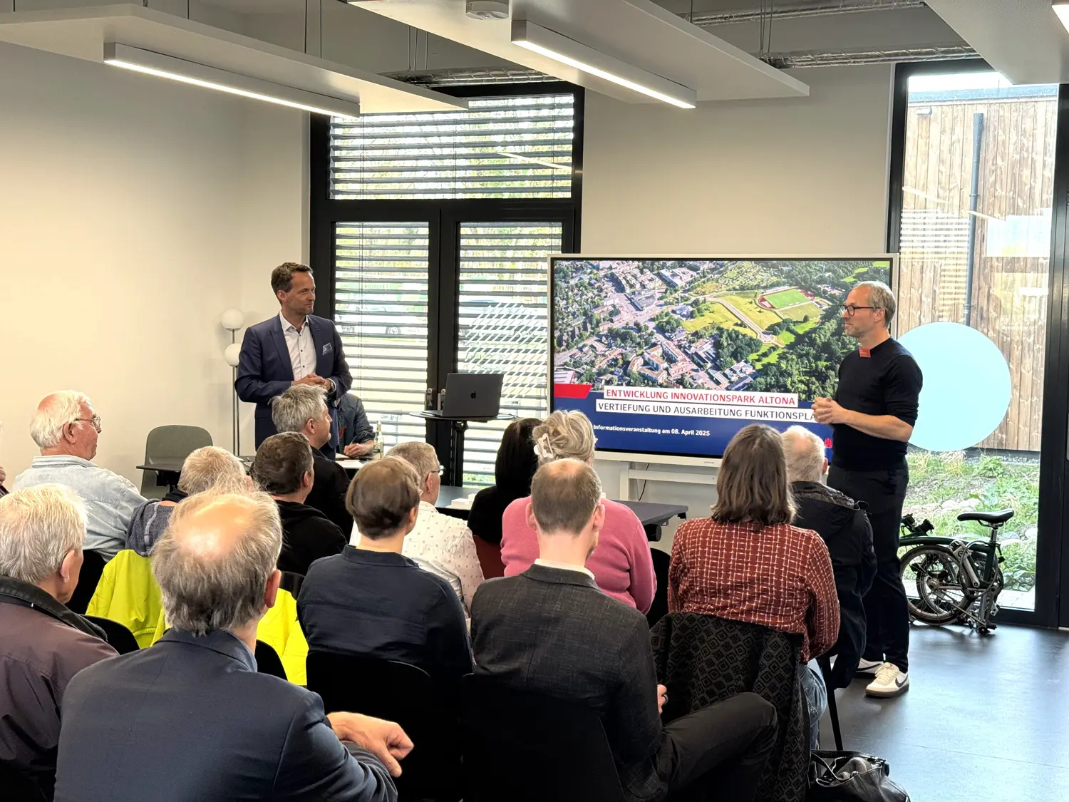 In einem Meetingraum präsentiert der HIE-Geschäftsführer dem Publikum gut gelaunt die Pläne für den Innovationspark Altona.