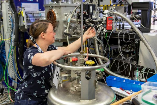 Eine Forscherin richtet eine technische Komponente an einem komplexen Experimentaufbau aus.