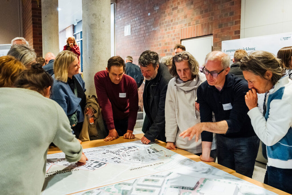 Several people are standing around a table, reviewing the functional plan for the neighborhoods near Volkspark.