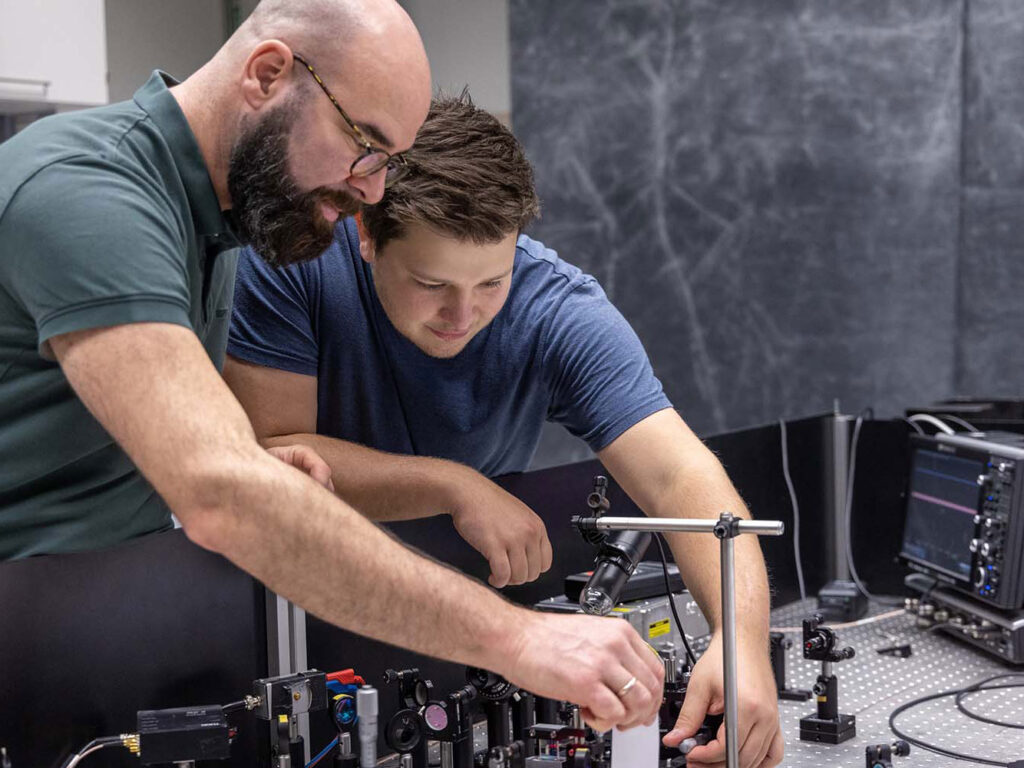 Zwei Personen arbeiten an einem wissenschaftlichen Gerät.